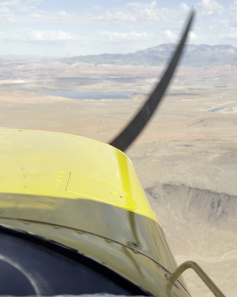 Pilot's view over the yellow cowling and spinning propeller of the Cessna 152, flying over the desert near Hurricane, Utah